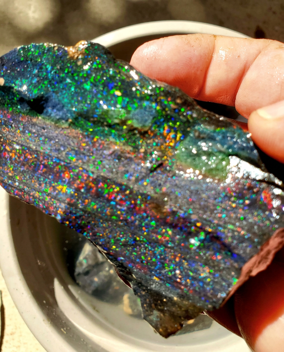 Hand-held opal specimen with blue, green and multicoloured flashes